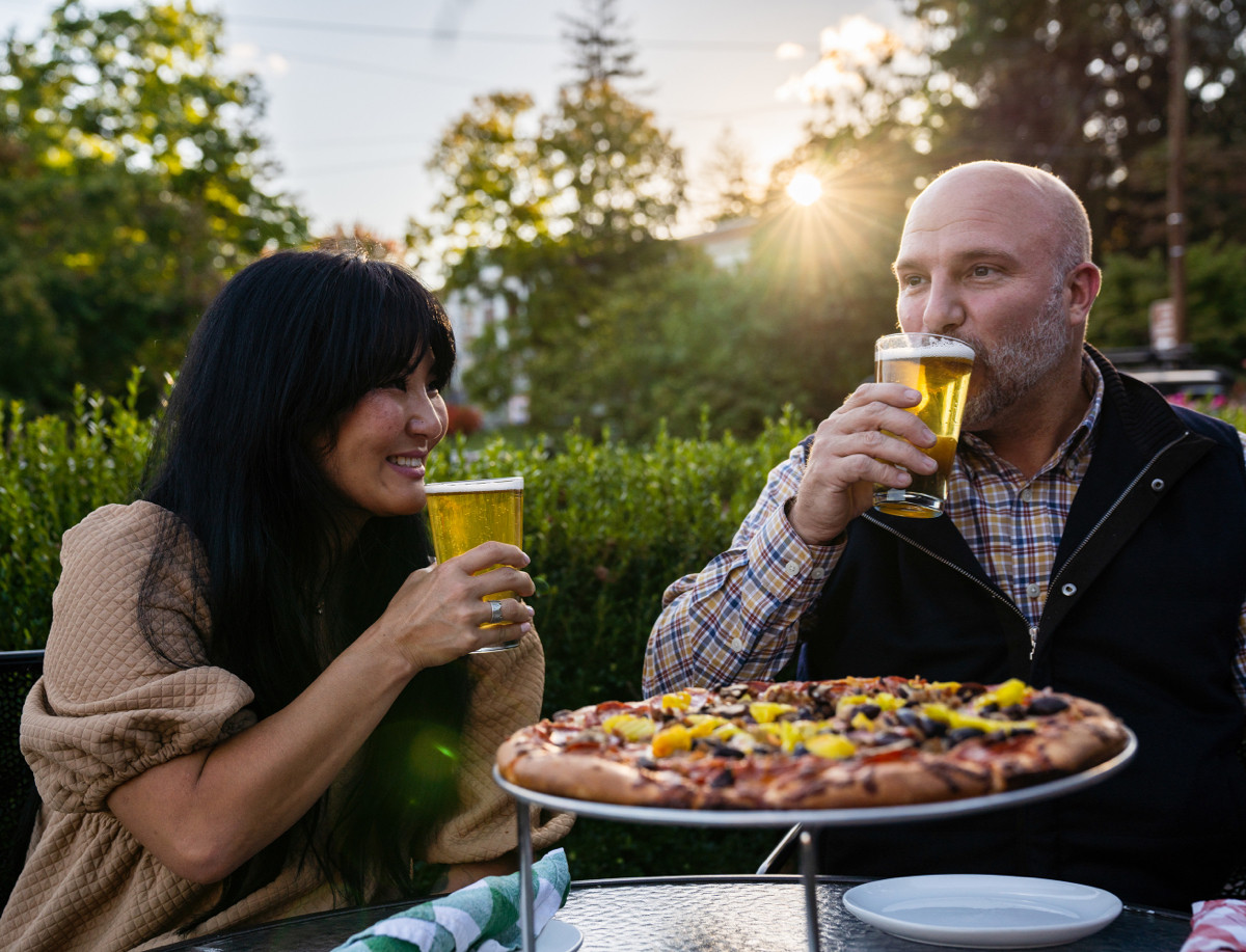 Dining outdoors drinking beer and eating pizza