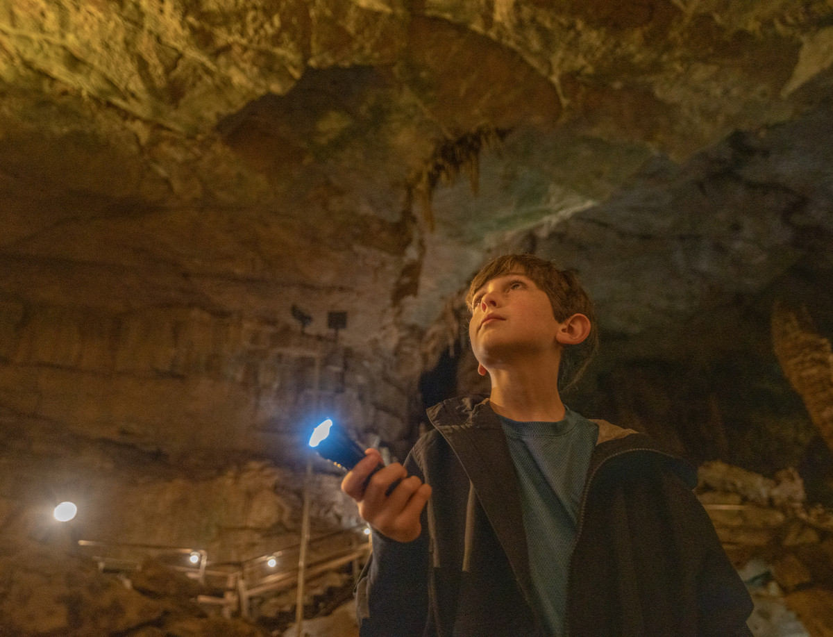 boy with flashlight in cave