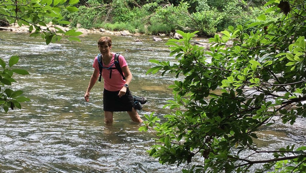 Woman wading through creek.