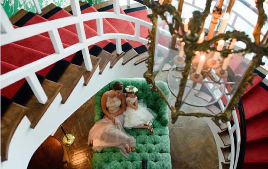 Bride and flower girl under spiral staircase.